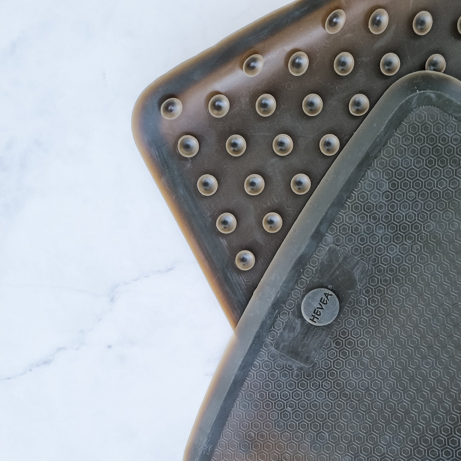 Two black rubber mats with textured surface on a white background