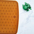 Honeycomb Anti Slip Baby Bath Mat in natural rubber with suction cups beside a green frog bath toy.