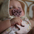 Baby holding a pink teething toy with a blurred background