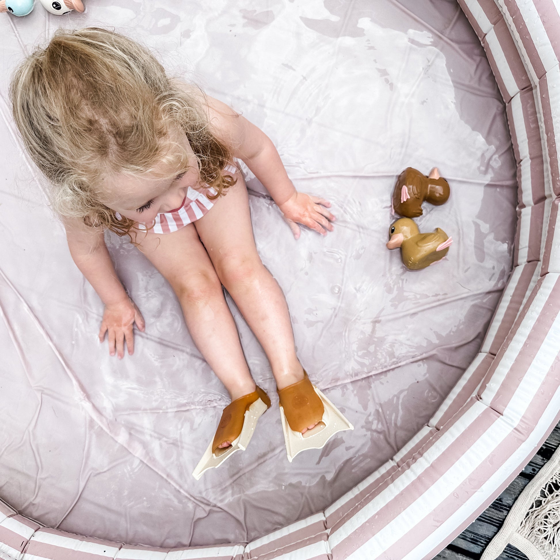 Child in a small pool with inflatable ring and toys