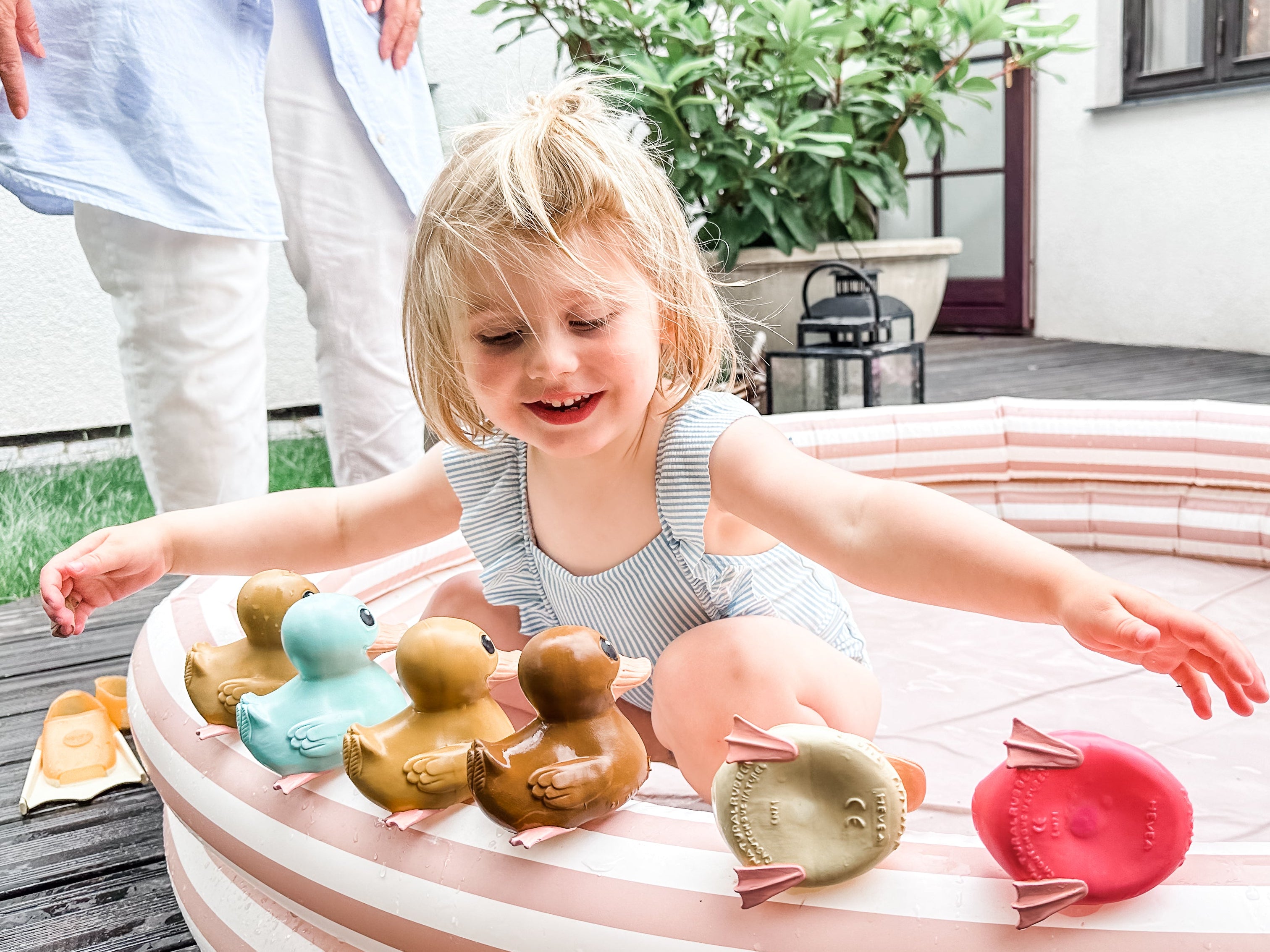 Child playing with rubber ducks in a small pool outdoors