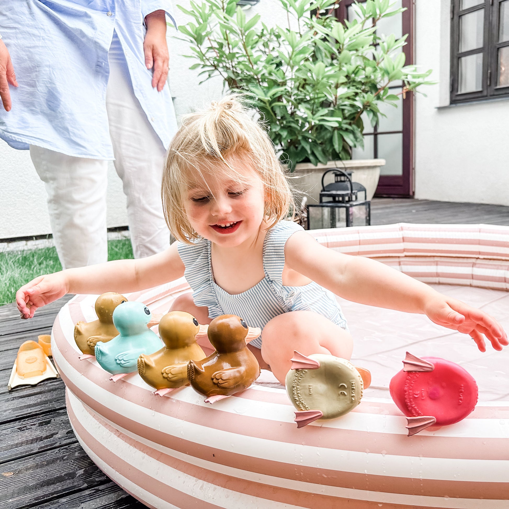 Child playing with rubber ducks in a small pool outdoors