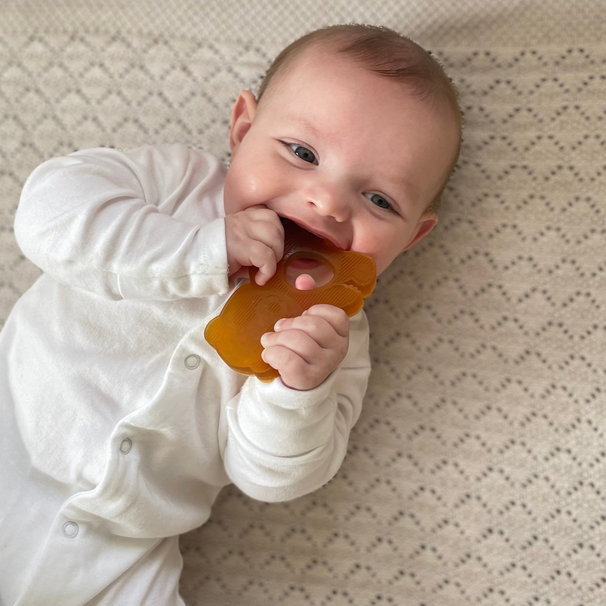 Baby lying on a textured surface with a yellow object