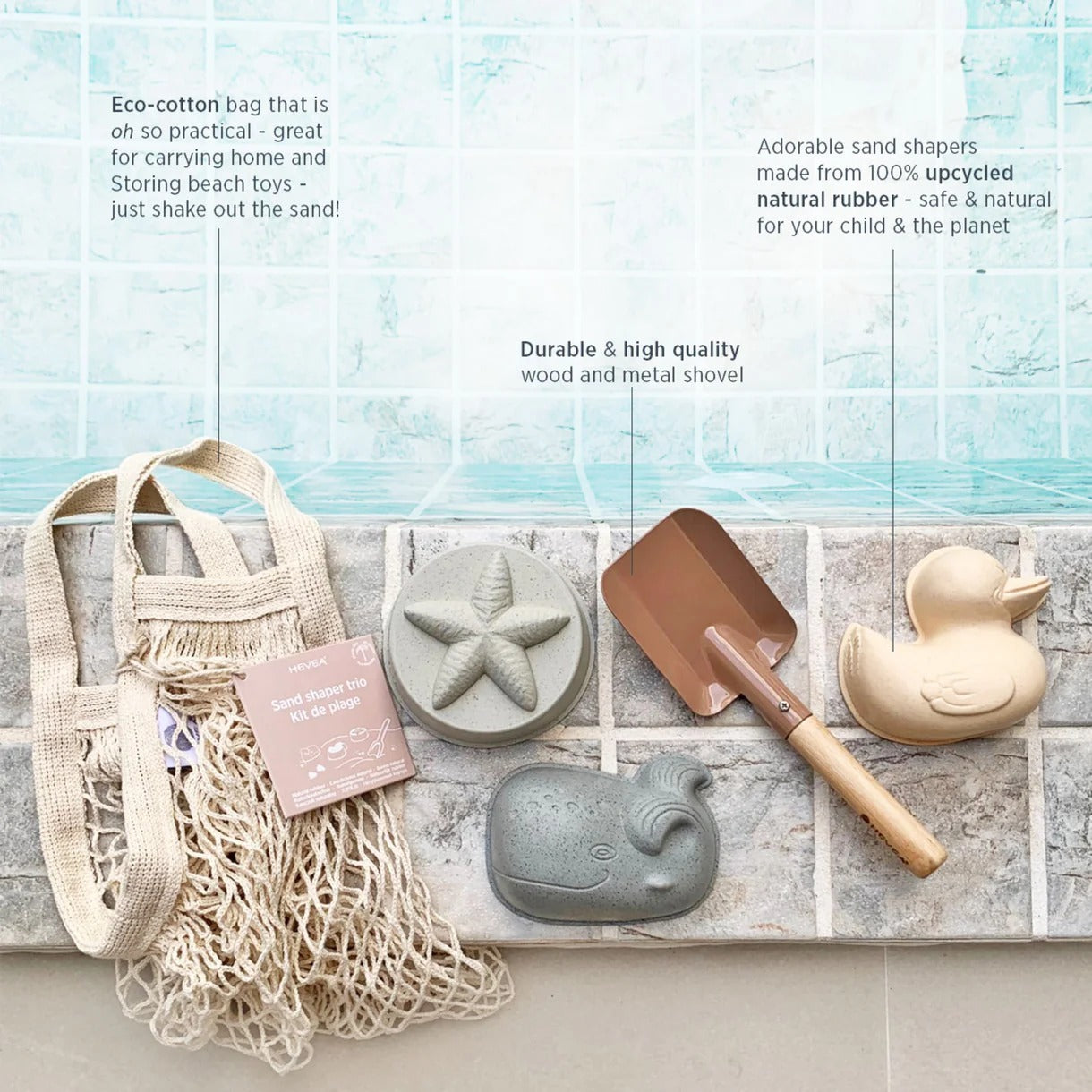 Eco-friendly sand toys and accessories on a stone surface with a beach-themed background.